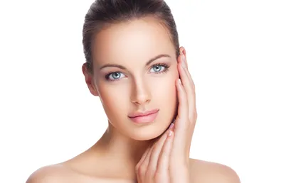 A photo of a young woman with healthy skin touching her face.